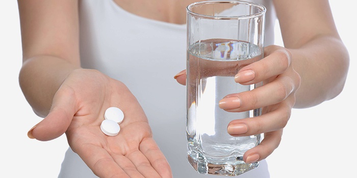 Женщина с таблетками и стаканом с водой