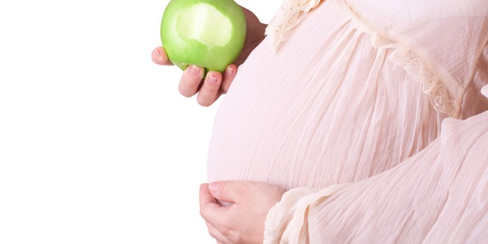 Беременная девушка с яблоком в руке