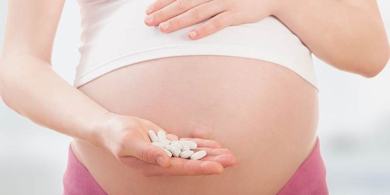 Беременная женщина с таблетками на ладони