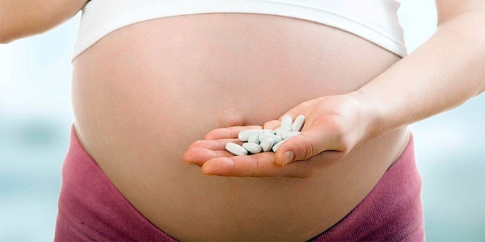 Беременная женщина с таблетками в руке