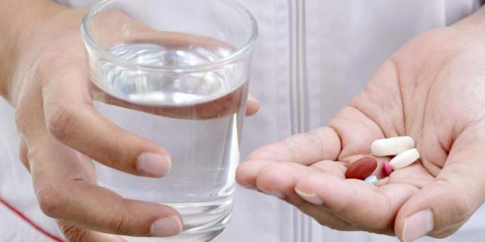 Лекарства и стакан воды в руках