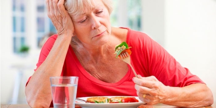 Пожилая женщина кушает салат