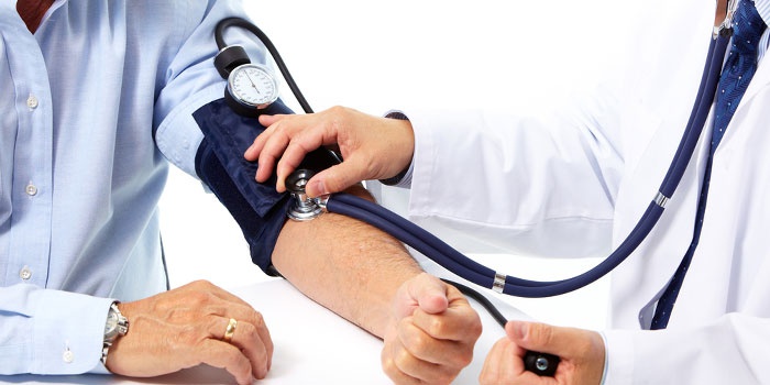 Медик измеряет артериальное давление у мужчин