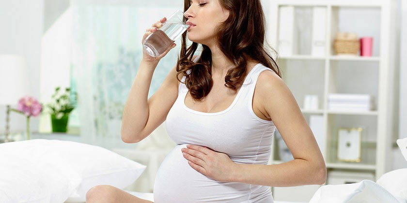 Беременная женщин пьет воду