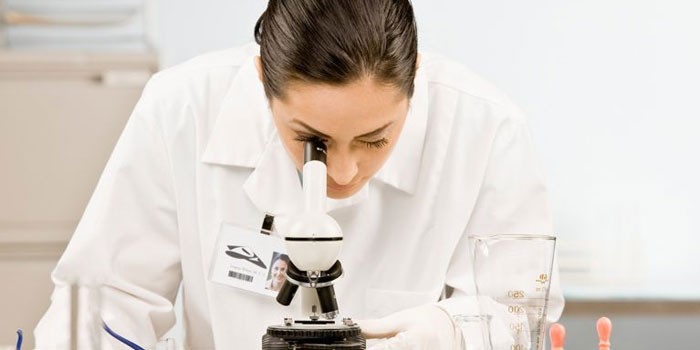 Девушка-лаборант смотрит в микроскоп
