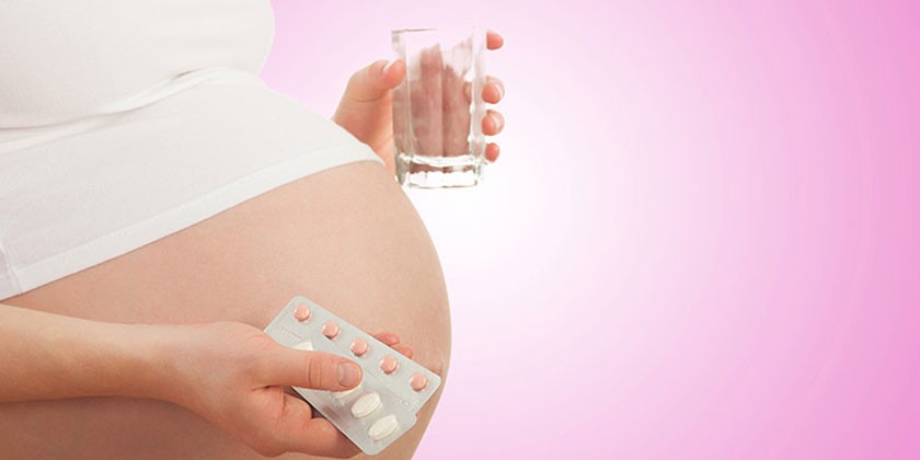 Беременная женщина с лекарствами и стаканом воды