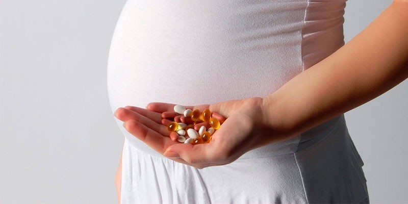 Беременная женщина с таблетками в ладоне