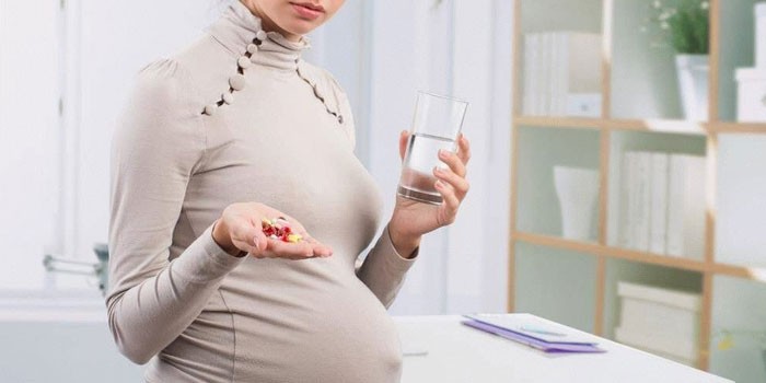 Беременная девушка с таблетками в руке