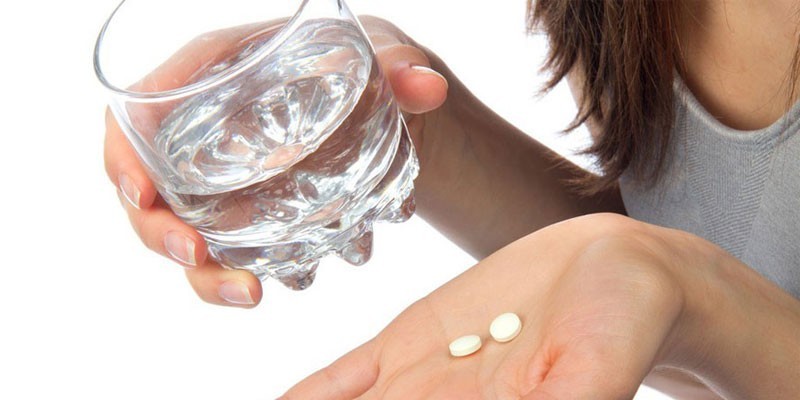 Лекарства и стакан воды в руках у девушки