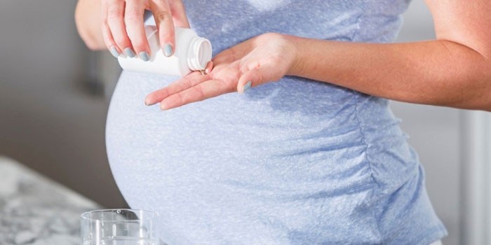 Беременная женщина с таблеткой в руке