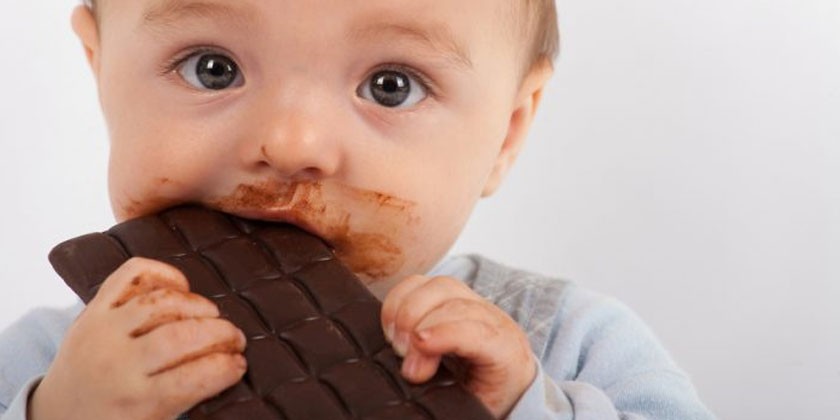 Маленький ребенок ест шоколад