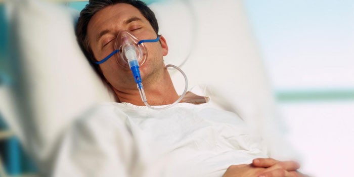 Мужчина в лежит в постели с кислородной маской на лице