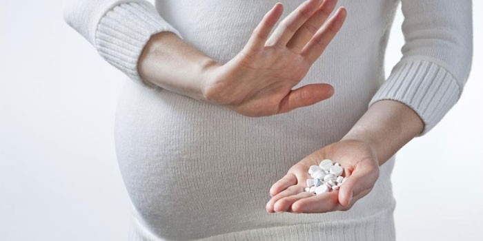Беременная женщина с таблетками в ладони