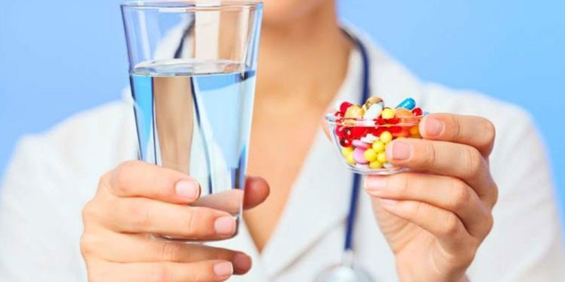 Медик с лекарствами и стаканом воды